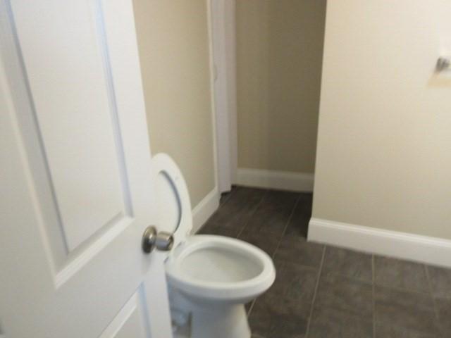 bathroom with toilet, baseboards, and tile patterned floors
