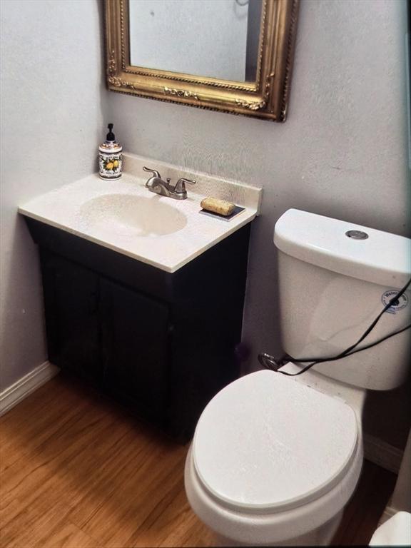 bathroom featuring wood-type flooring, vanity, and toilet