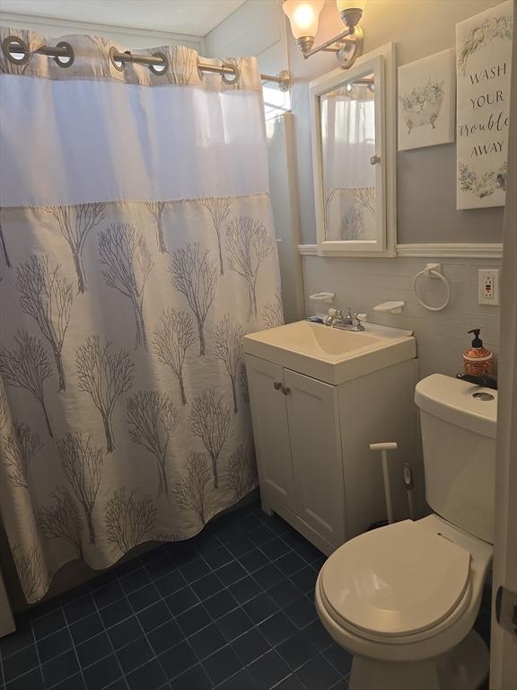 bathroom featuring vanity, tile walls, and toilet