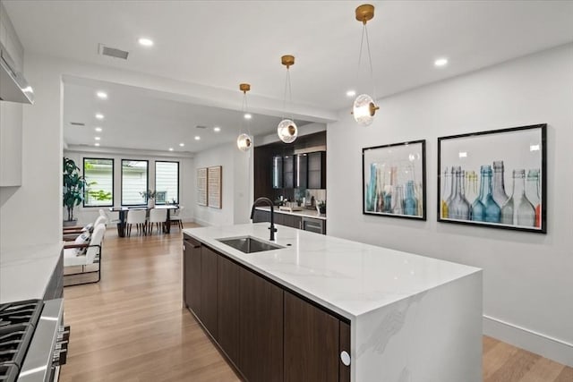 116 Thorndike Rd, Brookline, MA 02446 - kitchen featuring modern cabinets, dark brown cabinetry, light wood finished floors, a large island with sink, and recessed lighting