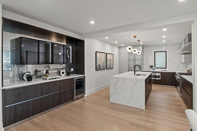 116 Thorndike Rd, Brookline, MA 02446 - kitchen featuring modern cabinets, wine cooler, appliances with stainless steel finishes, wall chimney exhaust hood, and a large island with sink