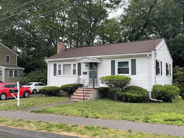 45 Leonard St, Dedham, MA 02026 - view of front facade with a chimney, a front yard, and roof with shingles