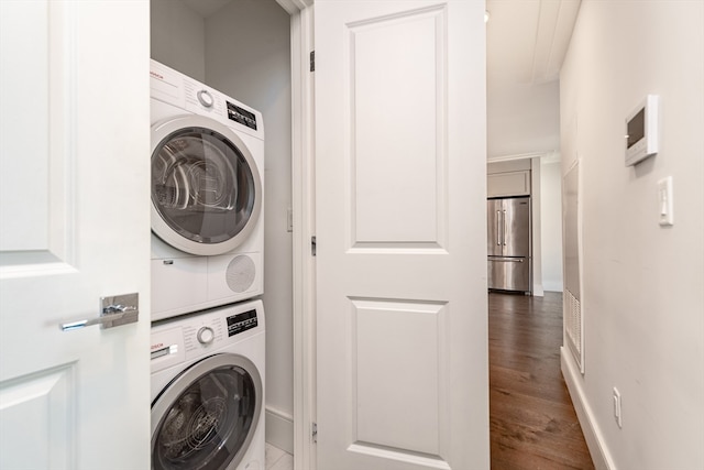 clothes washing area featuring dark wood-type flooring and stacked washer / drying machine