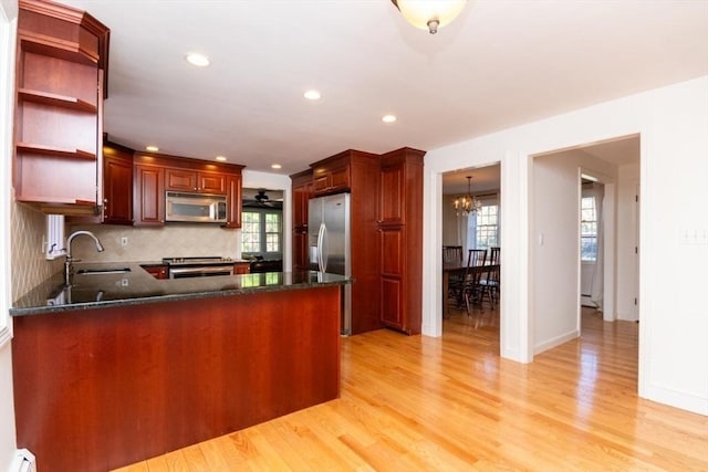 kitchen with an inviting chandelier, a baseboard heating unit, a sink, light wood finished floors, and stainless steel appliances