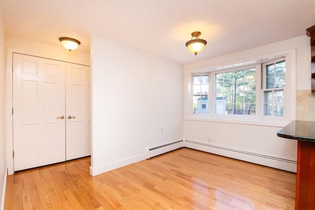unfurnished dining area featuring baseboards, baseboard heating, and light wood-style flooring