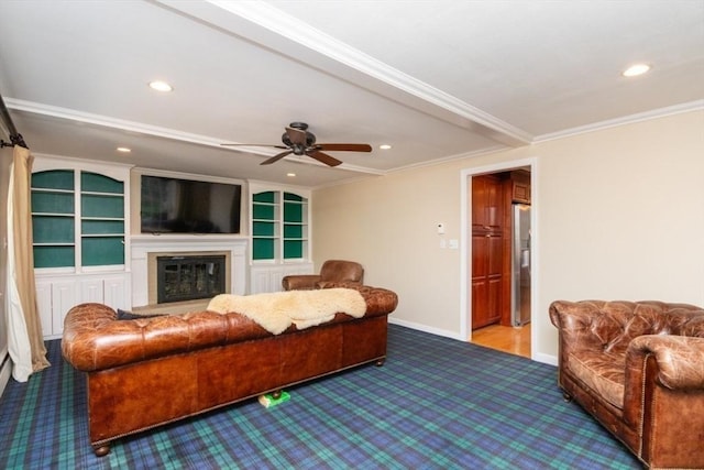 living room with baseboards, a glass covered fireplace, ornamental molding, carpet flooring, and recessed lighting