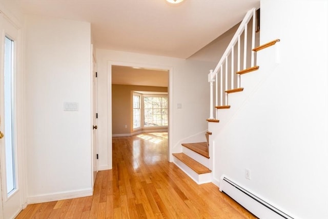 hall with baseboards, a baseboard heating unit, stairway, and light wood-type flooring