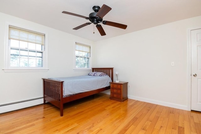 bedroom with baseboards, a ceiling fan, light wood-style flooring, and a baseboard heating unit