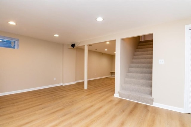 finished below grade area with stairs, recessed lighting, baseboards, and light wood-style floors
