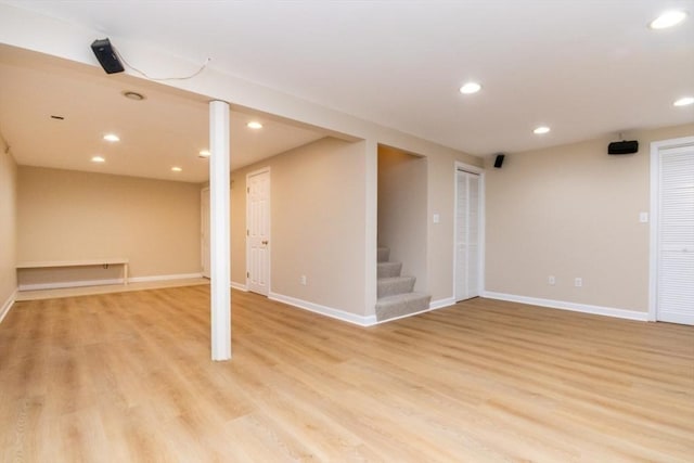 finished below grade area with recessed lighting, stairs, light wood finished floors, and baseboards
