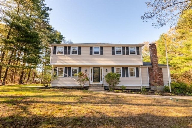 colonial-style house with a front yard and a chimney