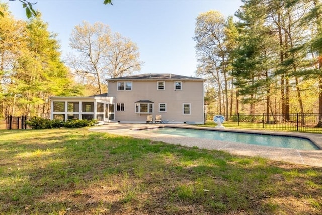 rear view of house with a lawn, a sunroom, fence, a fenced in pool, and a patio