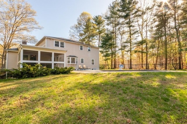 rear view of property with fence, a yard, a chimney, and a sunroom