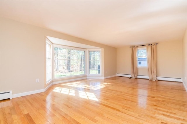 empty room featuring baseboards, baseboard heating, and light wood-style flooring