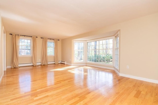 unfurnished room featuring baseboards, light wood finished floors, and a baseboard radiator