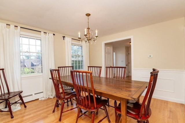 dining area with a chandelier, wainscoting, a healthy amount of sunlight, and light wood finished floors