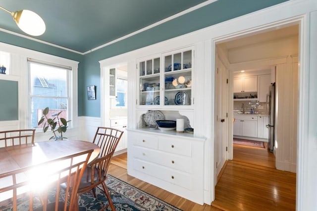 dining room featuring a wainscoted wall, light wood-type flooring, and crown molding