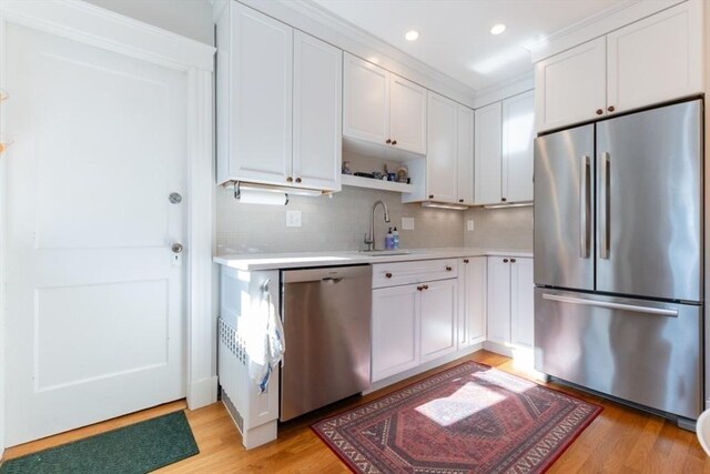 kitchen with stainless steel appliances, light wood-type flooring, a sink, and light countertops