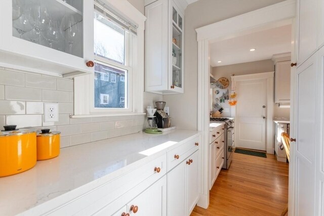 kitchen featuring stainless steel range with gas cooktop, white cabinetry, and decorative backsplash