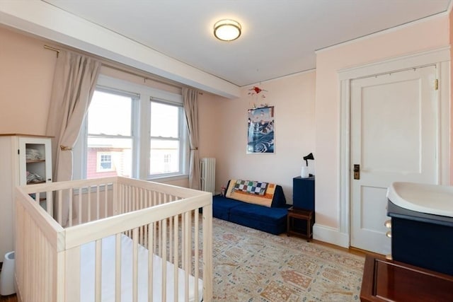 bedroom featuring a nursery area and radiator heating unit