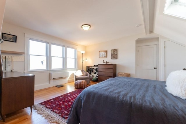 bedroom featuring vaulted ceiling with beams, baseboards, and wood finished floors