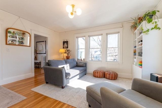 living area featuring light wood finished floors, an inviting chandelier, and baseboards