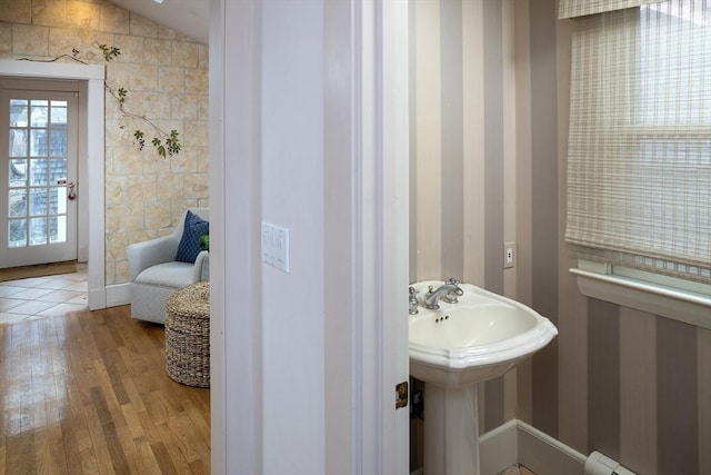 bathroom with vaulted ceiling, wood finished floors, and a sink