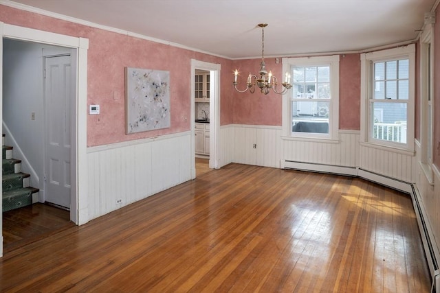 unfurnished dining area featuring stairway, wood-type flooring, and wainscoting