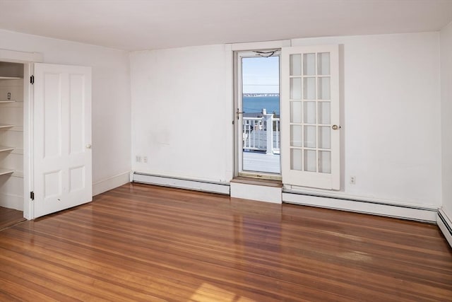 spare room with baseboard heating and wood finished floors