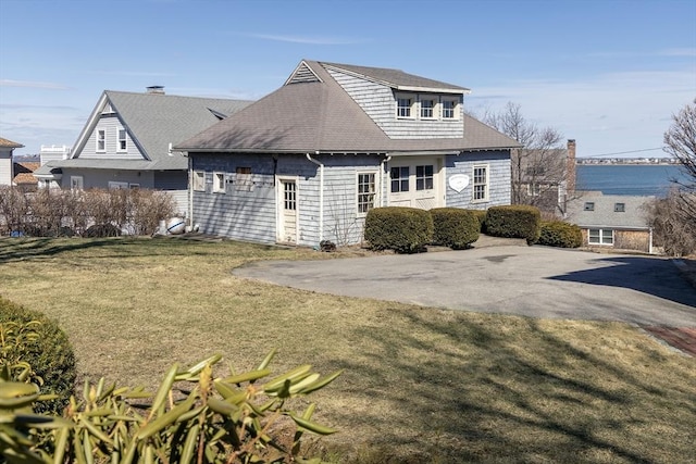 view of side of home featuring a lawn and roof with shingles