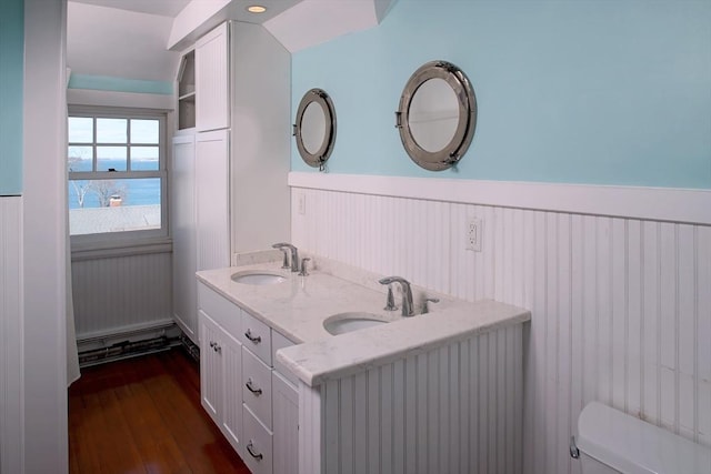 bathroom with toilet, wood finished floors, wainscoting, and a sink