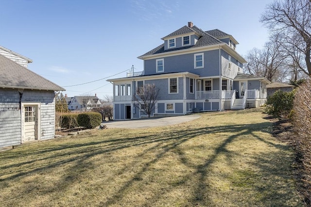 rear view of property featuring a lawn and covered porch