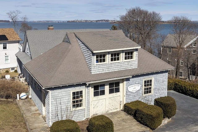 exterior space with a chimney, a garage, and a shingled roof