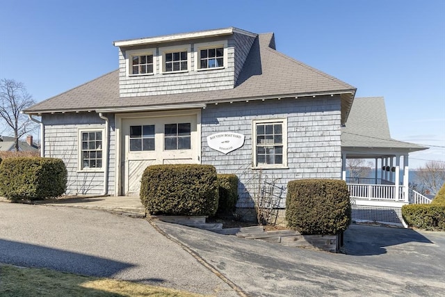 view of front of property featuring a garage, roof with shingles, covered porch, and driveway