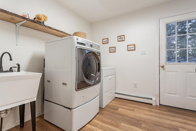 washroom with sink, washing machine and dryer, light hardwood / wood-style floors, and baseboard heating