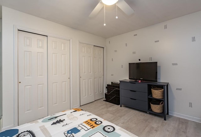 bedroom featuring multiple closets, ceiling fan, and light hardwood / wood-style flooring