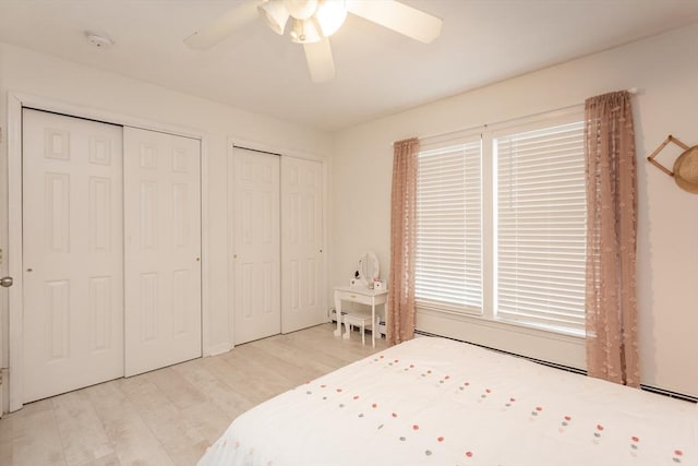 bedroom featuring multiple closets, ceiling fan, and light wood-type flooring