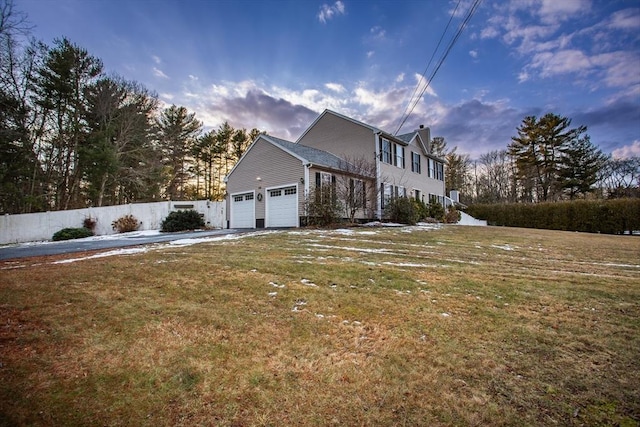 property exterior at dusk featuring a garage and a yard