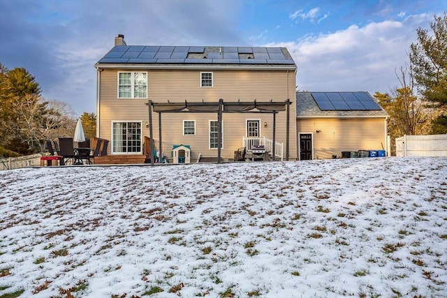 snow covered back of property featuring a pergola