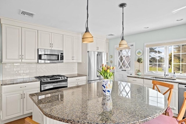 kitchen featuring stainless steel appliances, a sink, white cabinets, backsplash, and recessed lighting