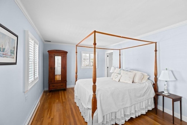 bedroom with wood finished floors, baseboards, crown molding, and baseboard heating