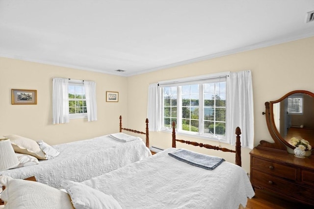 bedroom with ornamental molding and a baseboard heating unit