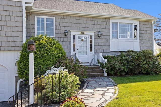 property entrance featuring a yard and roof with shingles