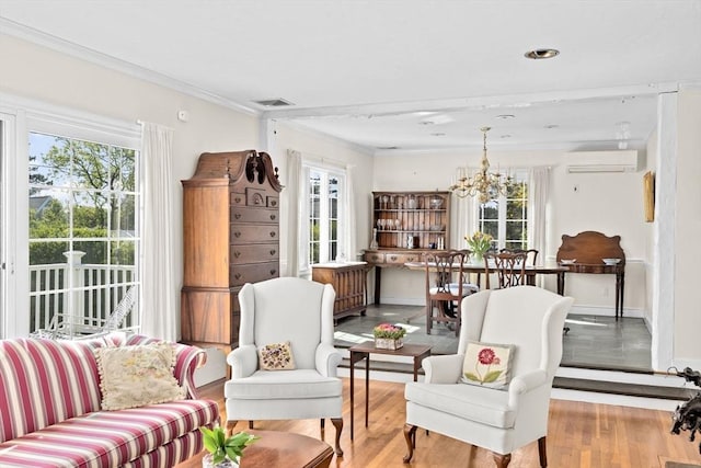 living area featuring an AC wall unit, a chandelier, crown molding, wood finished floors, and baseboards