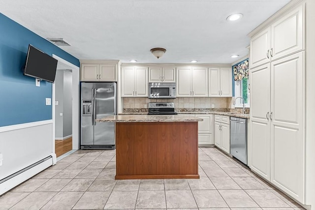 kitchen with stainless steel appliances, a baseboard radiator, light tile patterned flooring, decorative backsplash, and light stone counters