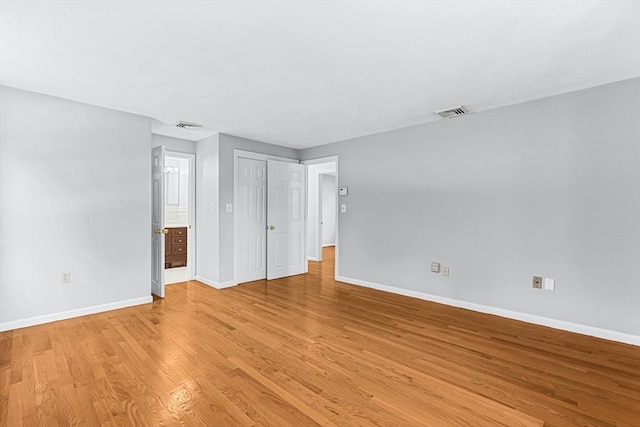 unfurnished bedroom with baseboards, light wood-type flooring, and ensuite bath
