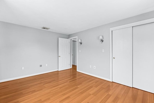 unfurnished bedroom with light wood-style flooring, baseboards, and a closet