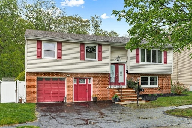 bi-level home with a garage, driveway, and brick siding