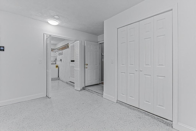 unfurnished bedroom with baseboards, a closet, and washer / dryer