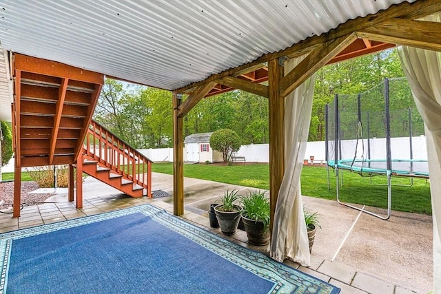 view of patio / terrace featuring a trampoline, stairway, a storage shed, and an outdoor structure